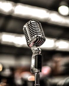 Close-up of a vintage chrome microphone on a blurred stage background, ideal for music themes.